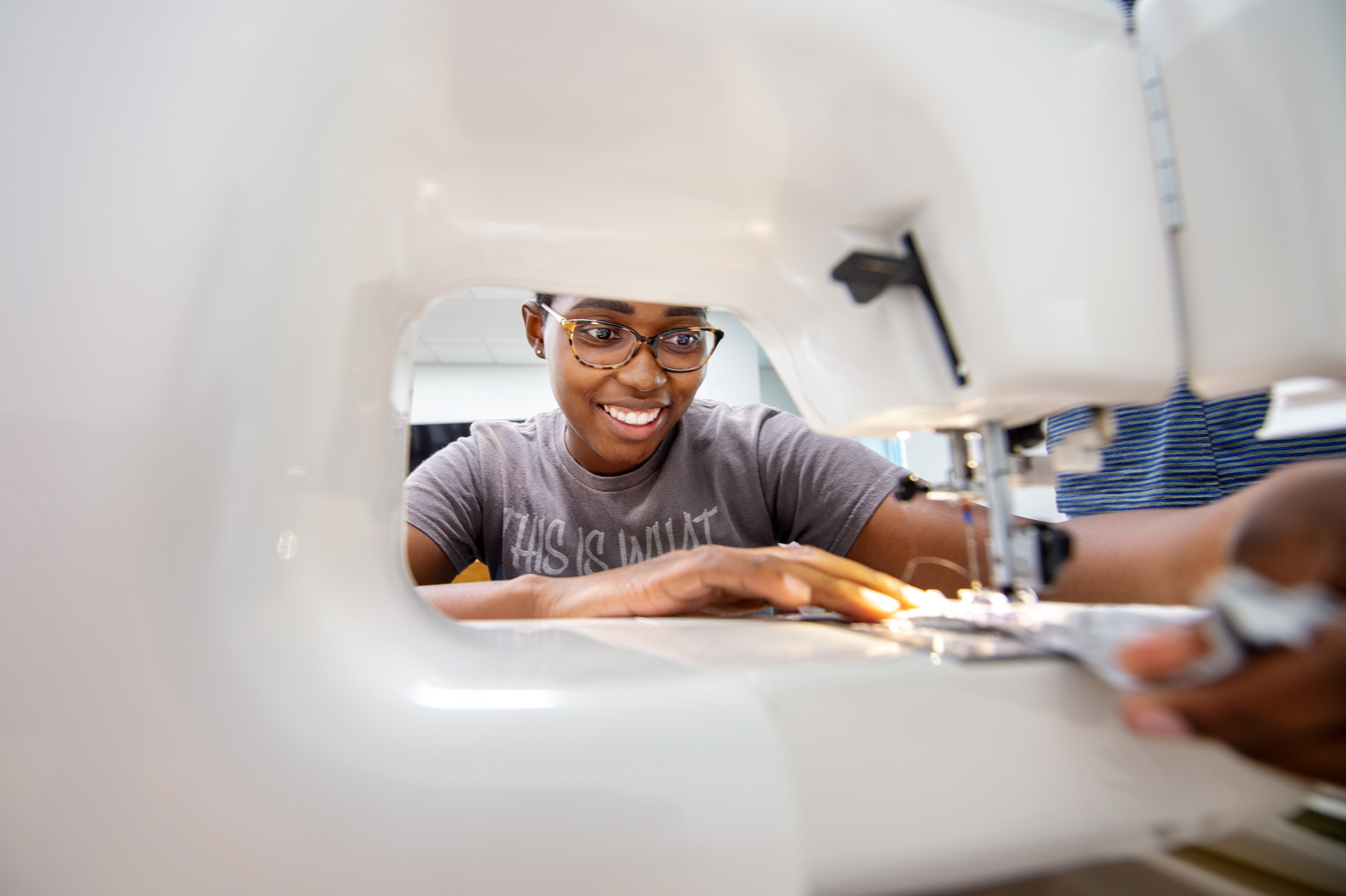 Framed by her sewing machine, Biomedical Engineering student Christina Moffett practices her beginning sewing skills.