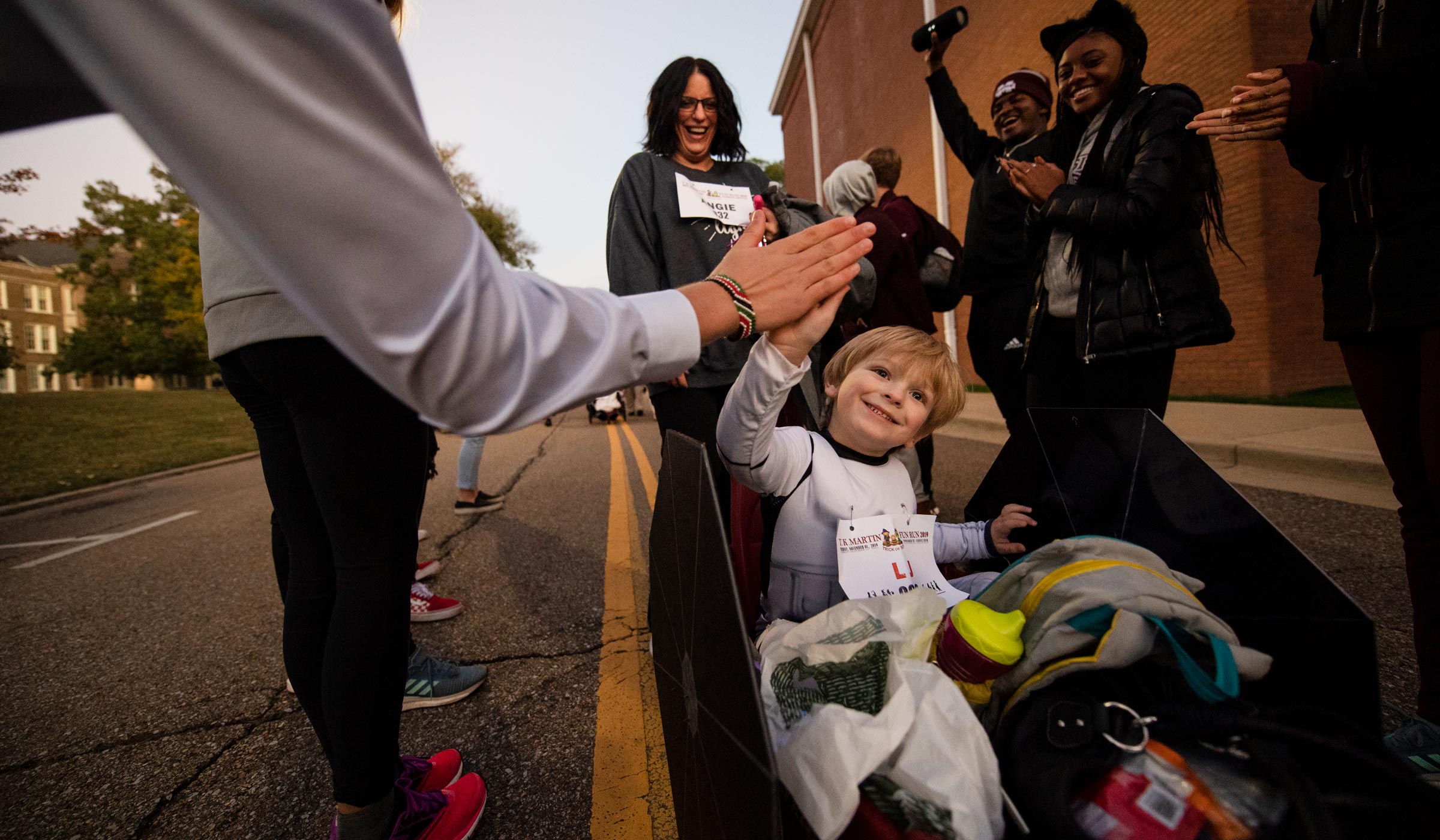 LJ Carnathan gives a high five to a participant at a cheer station during the T.K. Martin Fun Run.