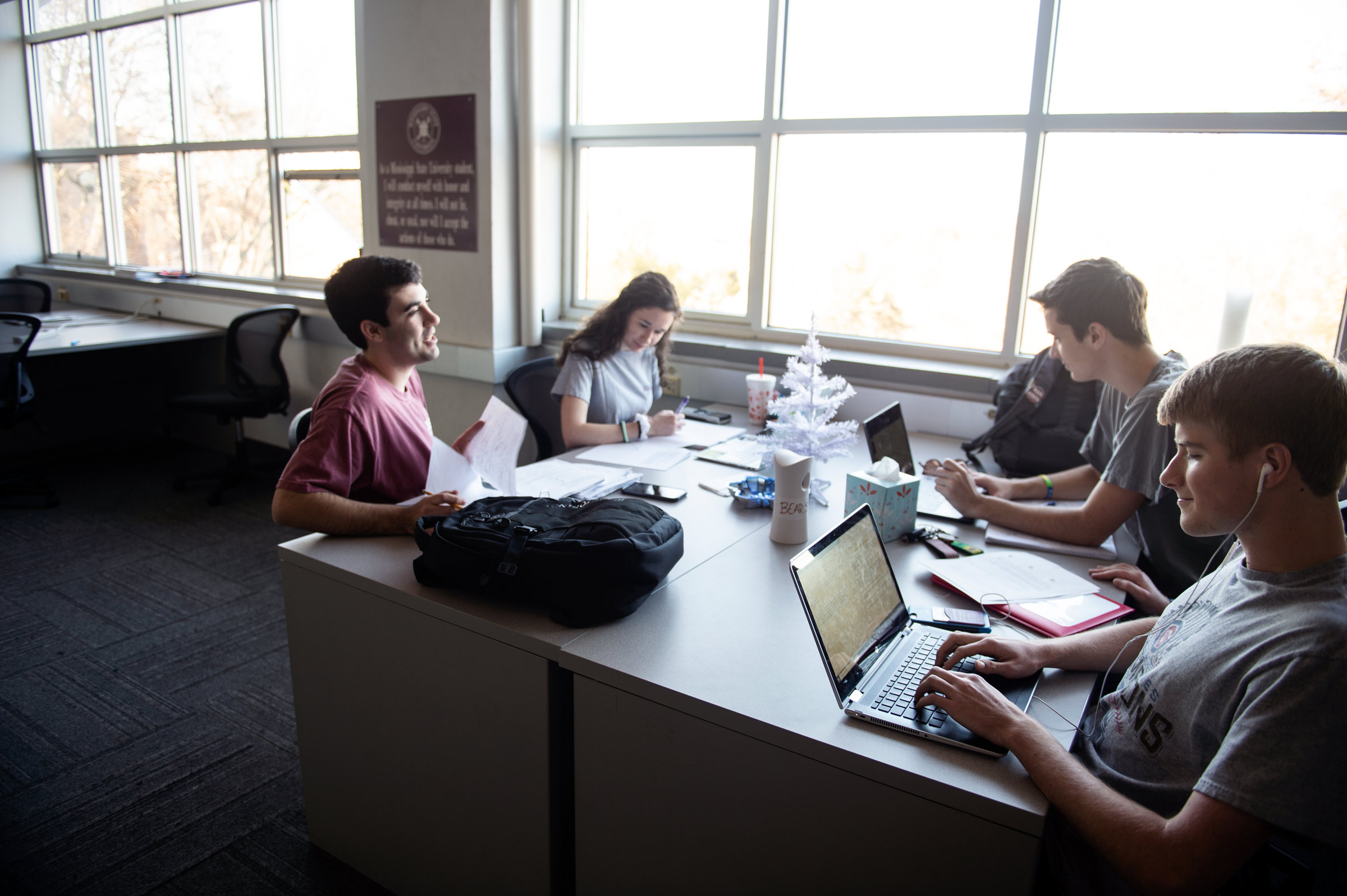 Four geosciences students study for December finals in a Hilbun study lab with a small Christmas tree in the table&#039;s center.