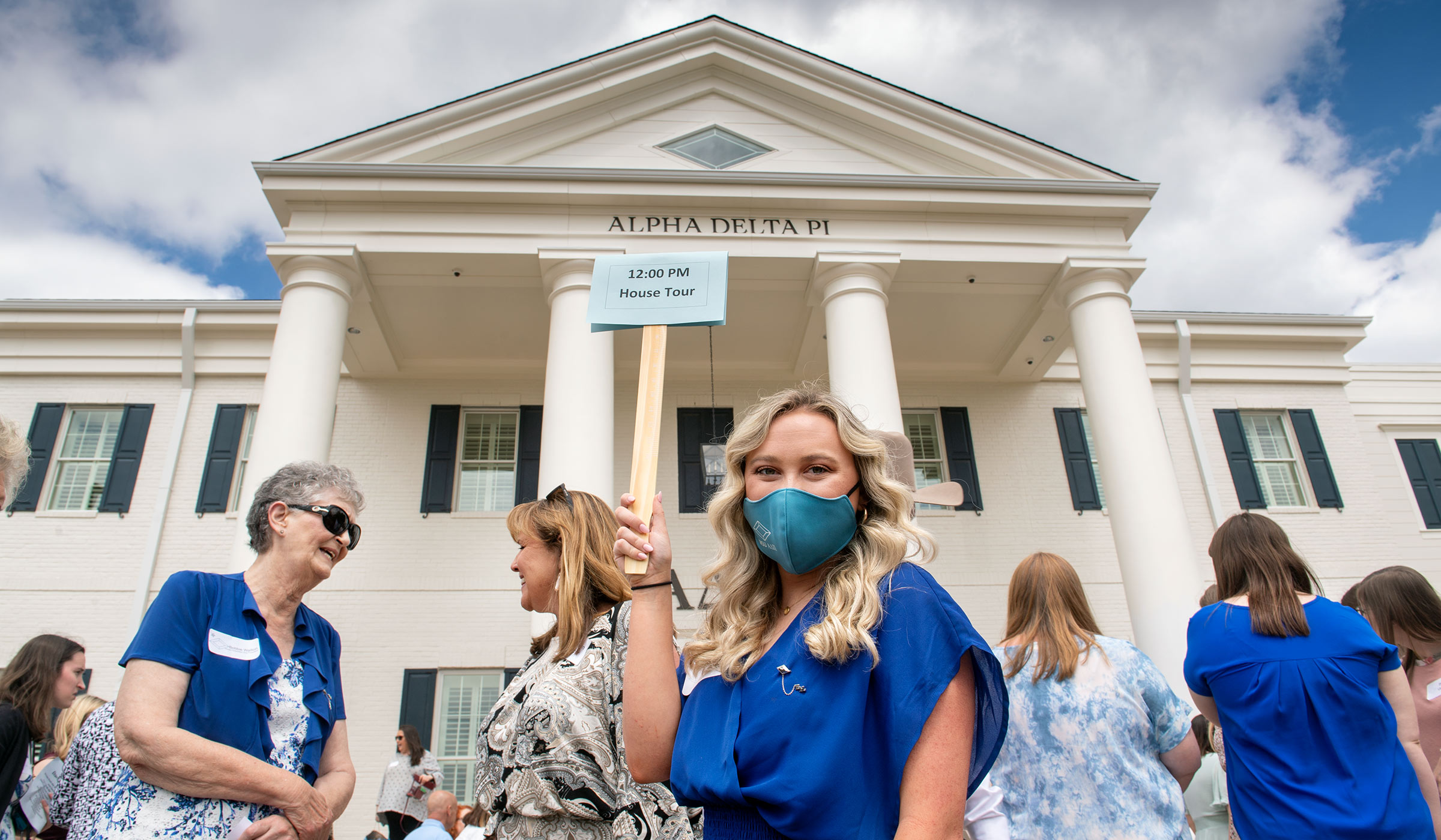 In the midst of crowds gathered for the dedication of the new Alpha Delta Pi sorority house, Mallory Stubbs holds up a sign for the 12:00 house tour. 