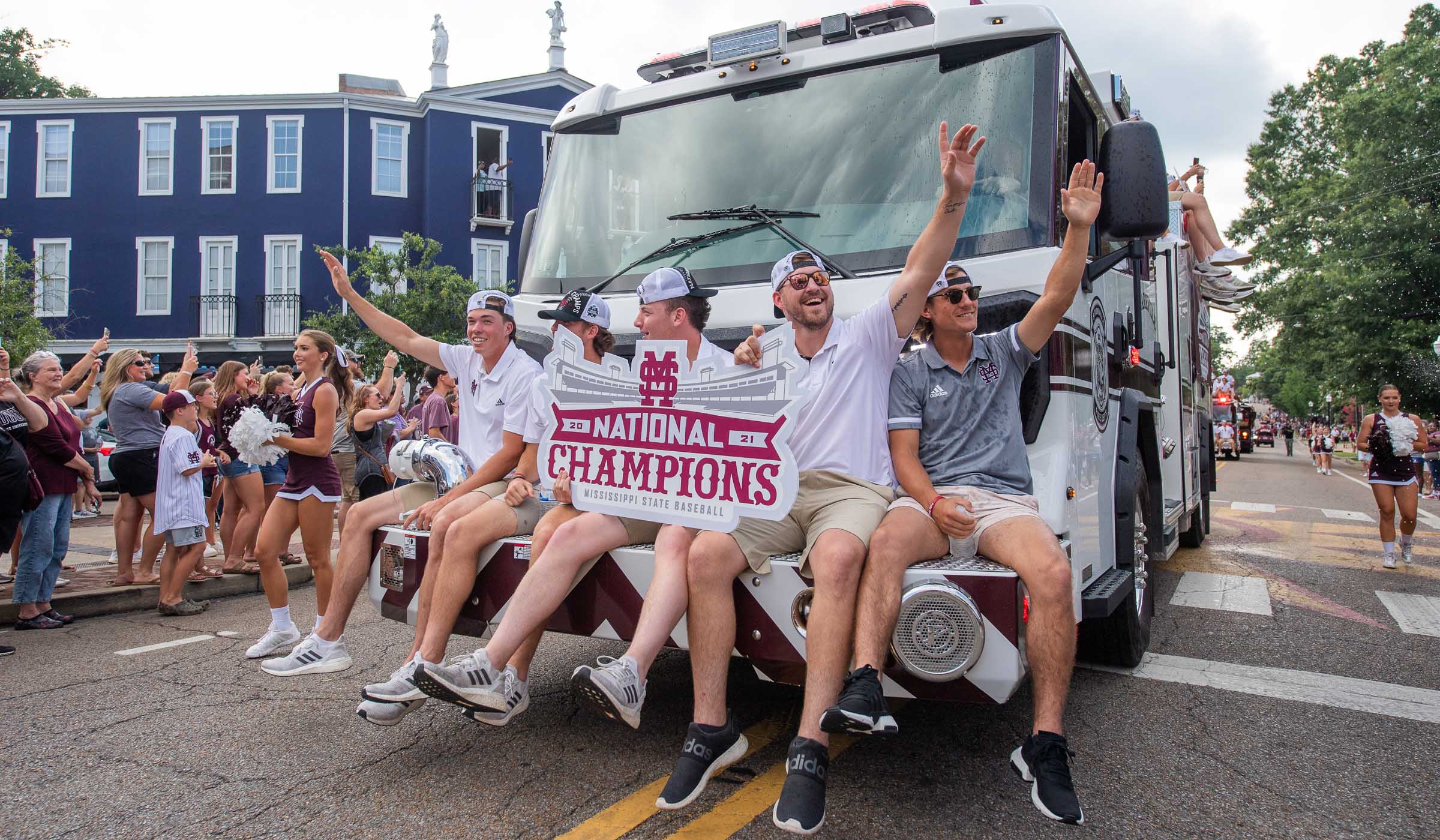 Guys in polos and khaki shorts on front of fire truck with signs saying National Champions