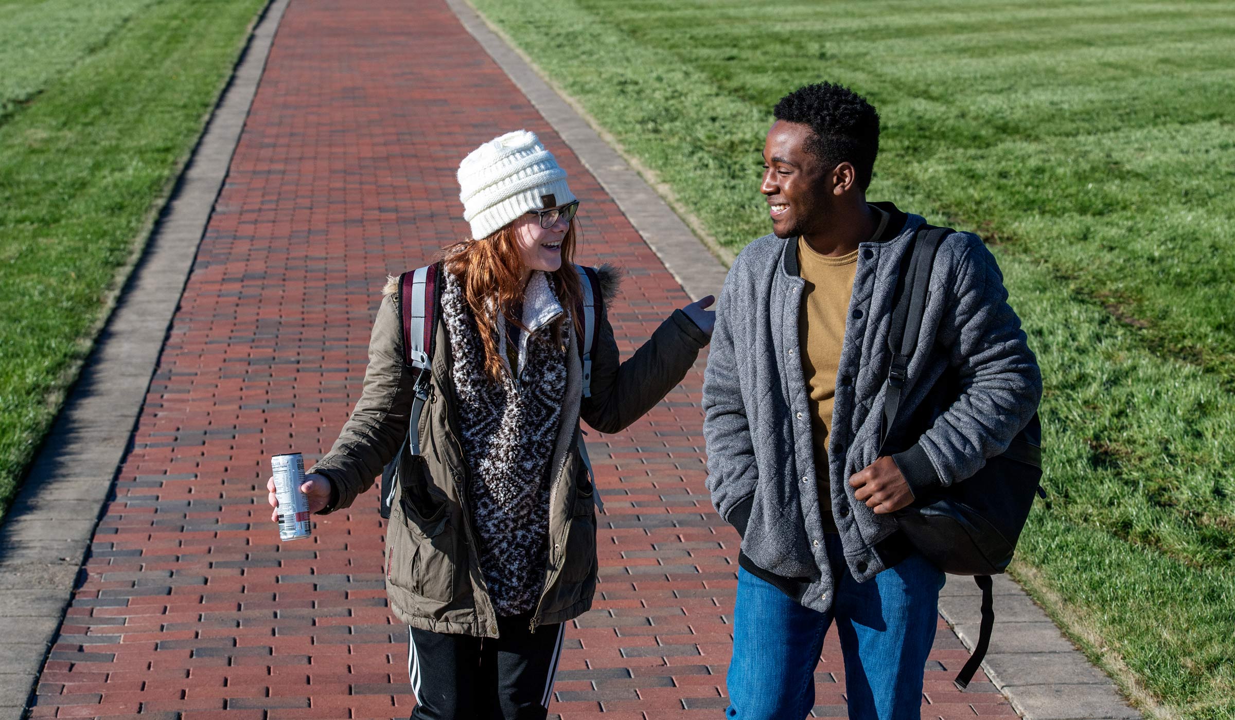Dressed to ward of the morning chill, two students share a laugh as they walk on a Drill Field Sidewalk.