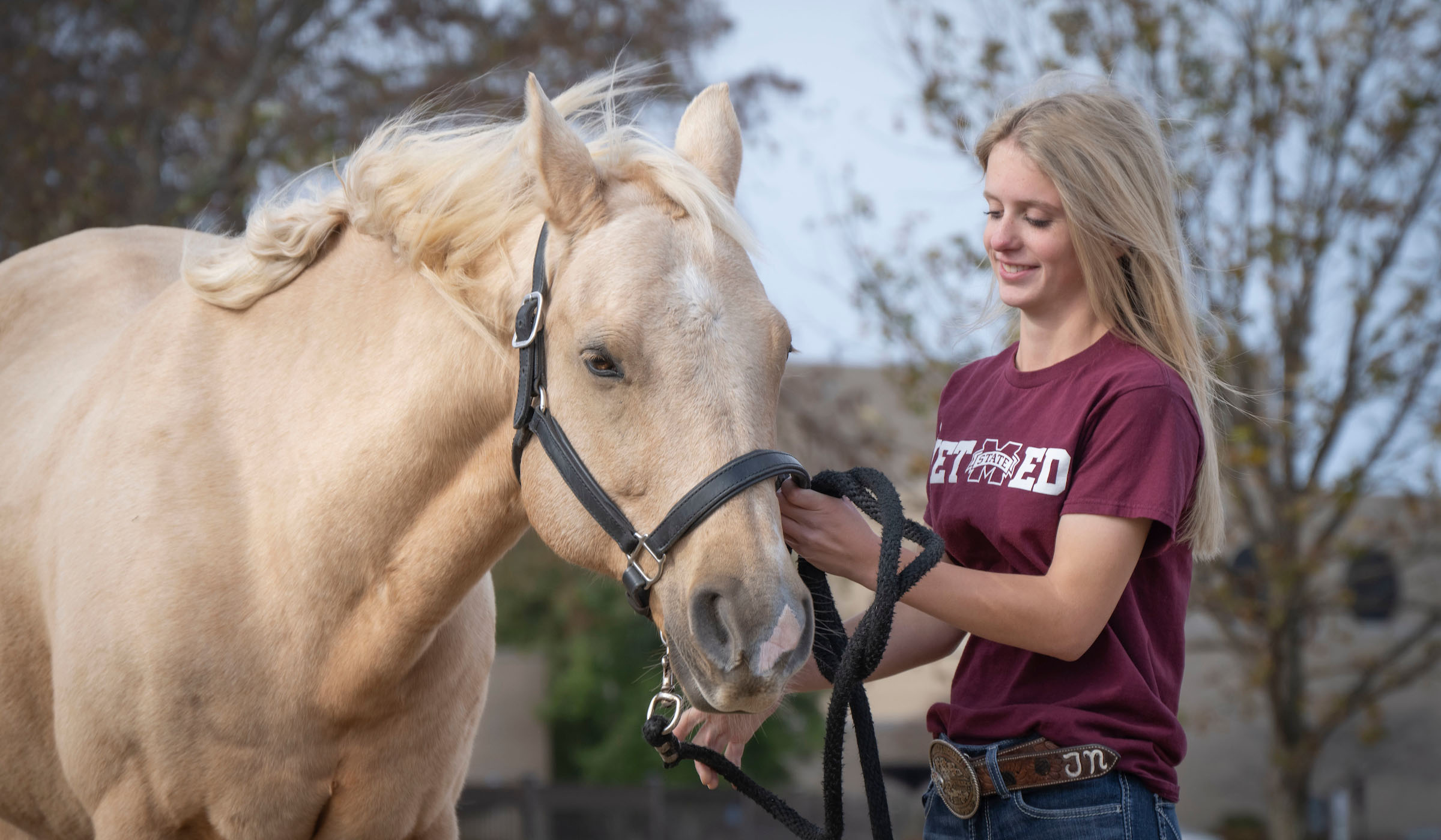 Joy Nabors pets a horse in front of MSU&#039;s College of Veterinary Medicine