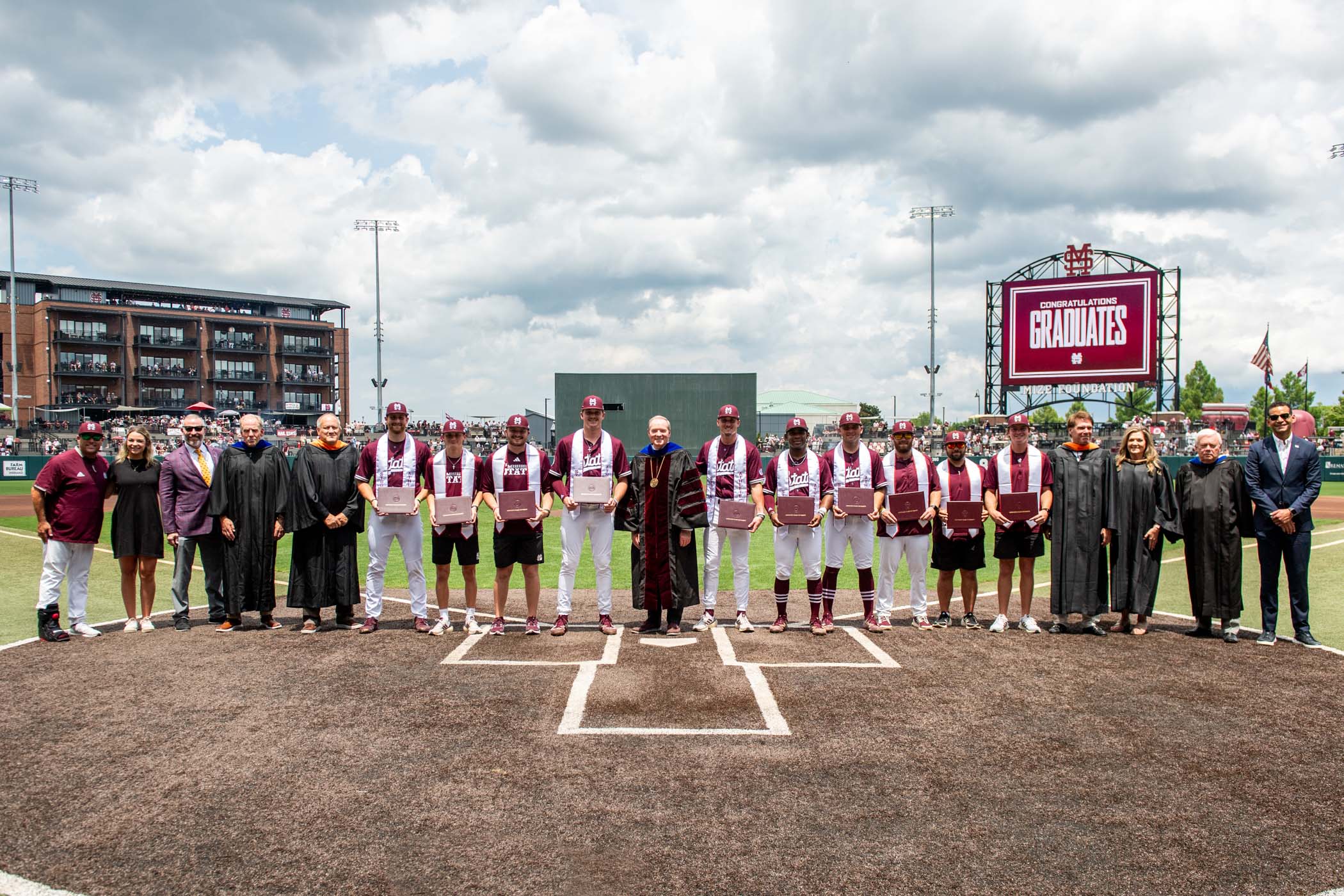 MSU President Mark E. Keenum and members of the Mississippi Institutions of Higher Learning Board of Trustees stand with graduating seniors of the university&#039;s baseball team during a special pre-game commencement ceremony before the Diamond Dawgs&#039; Friday game against the Missouri Tigers.