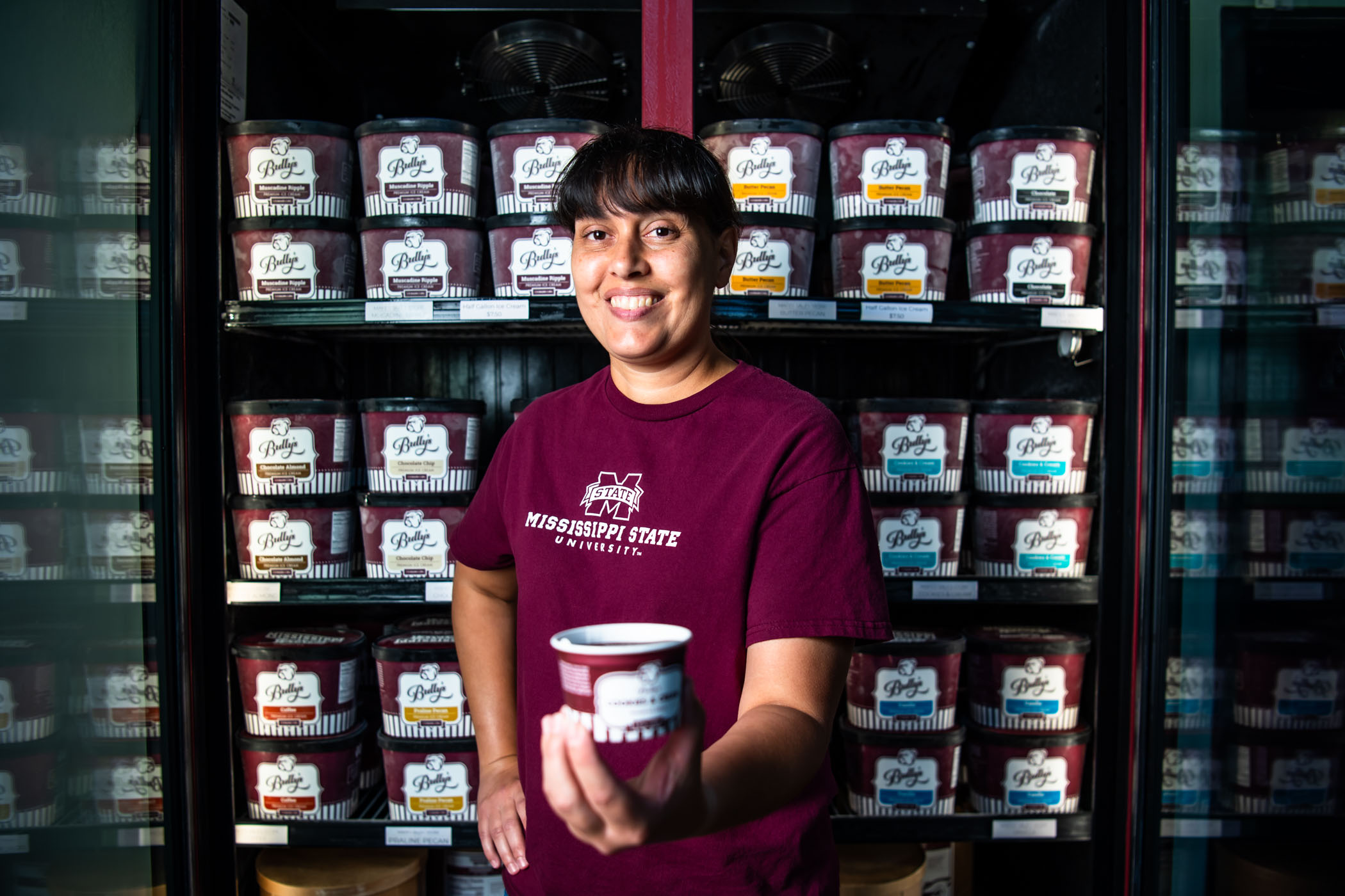 Angela Knight holding MSU ice cream in front of an ice cream freezer