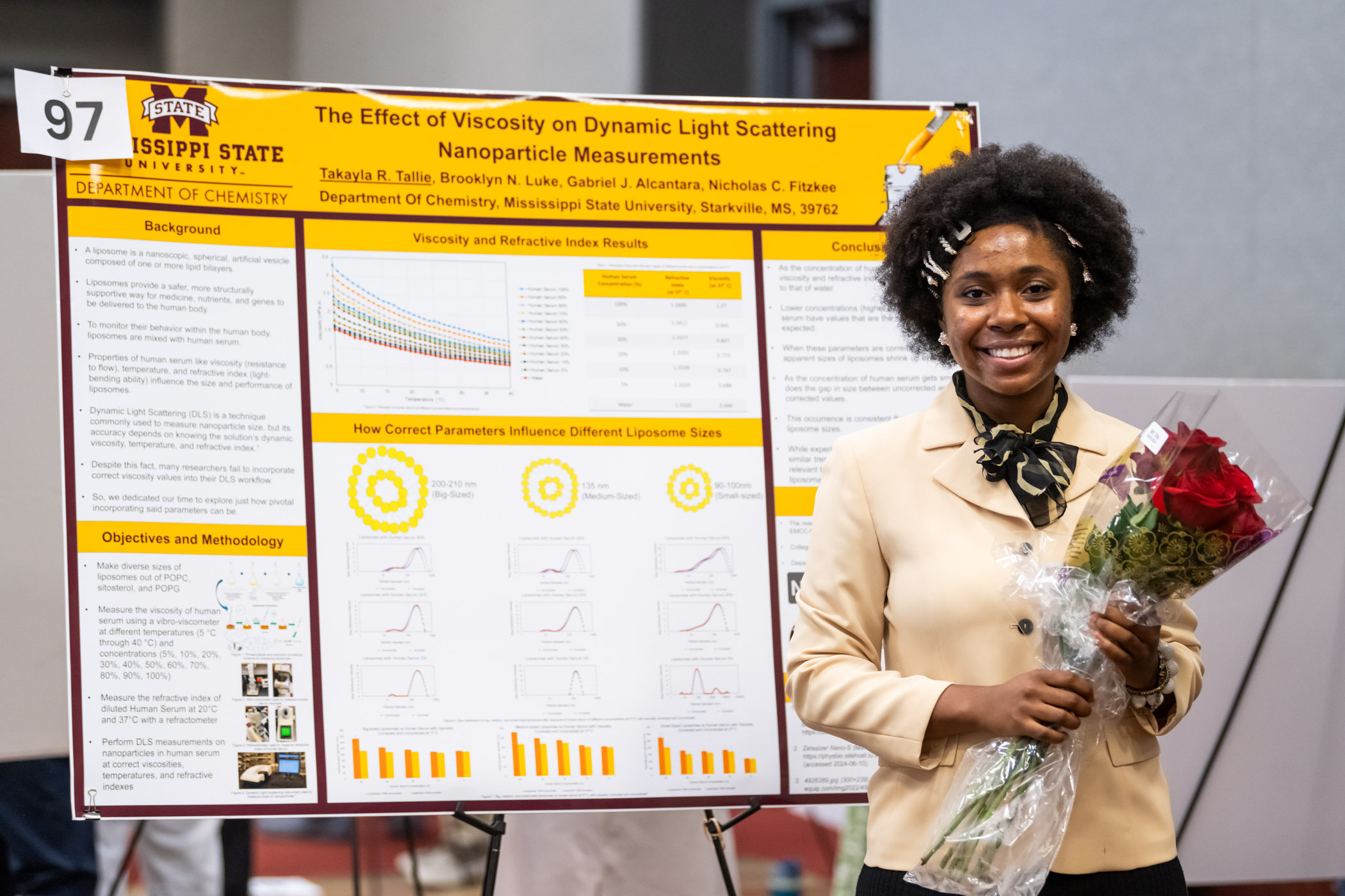 Takayla Tallie, a senior studying Chemistry, clutches a bouquet of maroon roses, a gift from her family for her diligent research efforts after her poster presentation at Shackouls Honors College&#039;s summer Undergraduate Research Showcase. Tallie, along with over one hundred other students, lined the Union Ballroom, seizing the opportunity to showcase faculty-guided research and creative activity. 