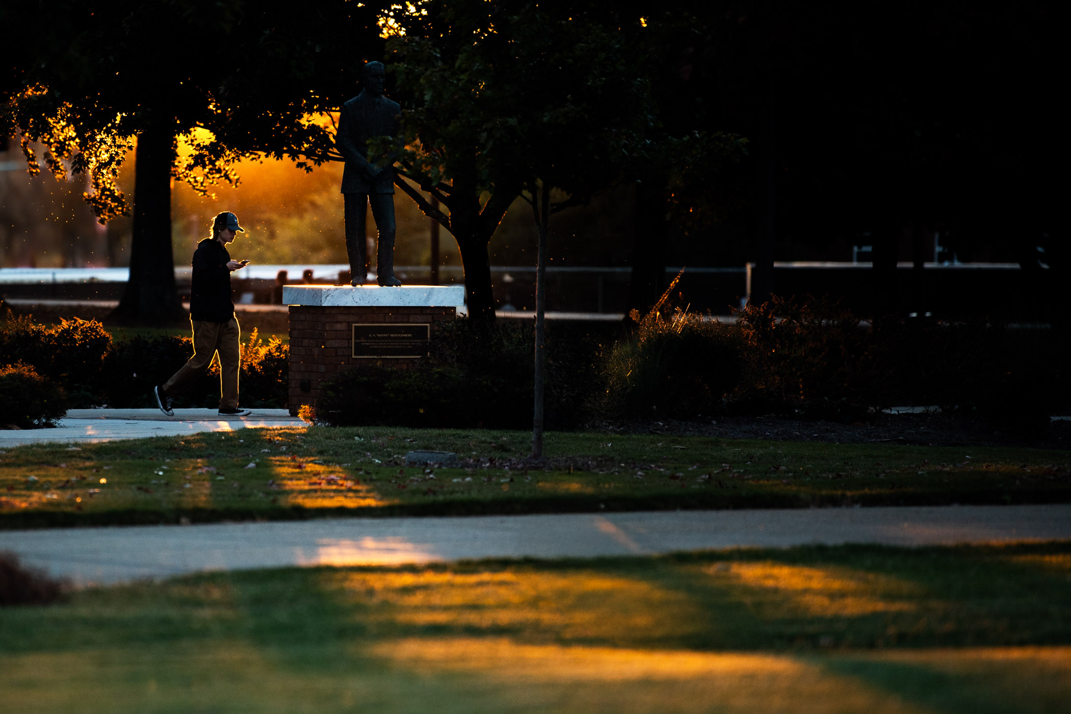 A benefit from "falling back" as part of daylight saving time, rich golden light outlines a strolling passerby and highlights campus with an early sunset.
