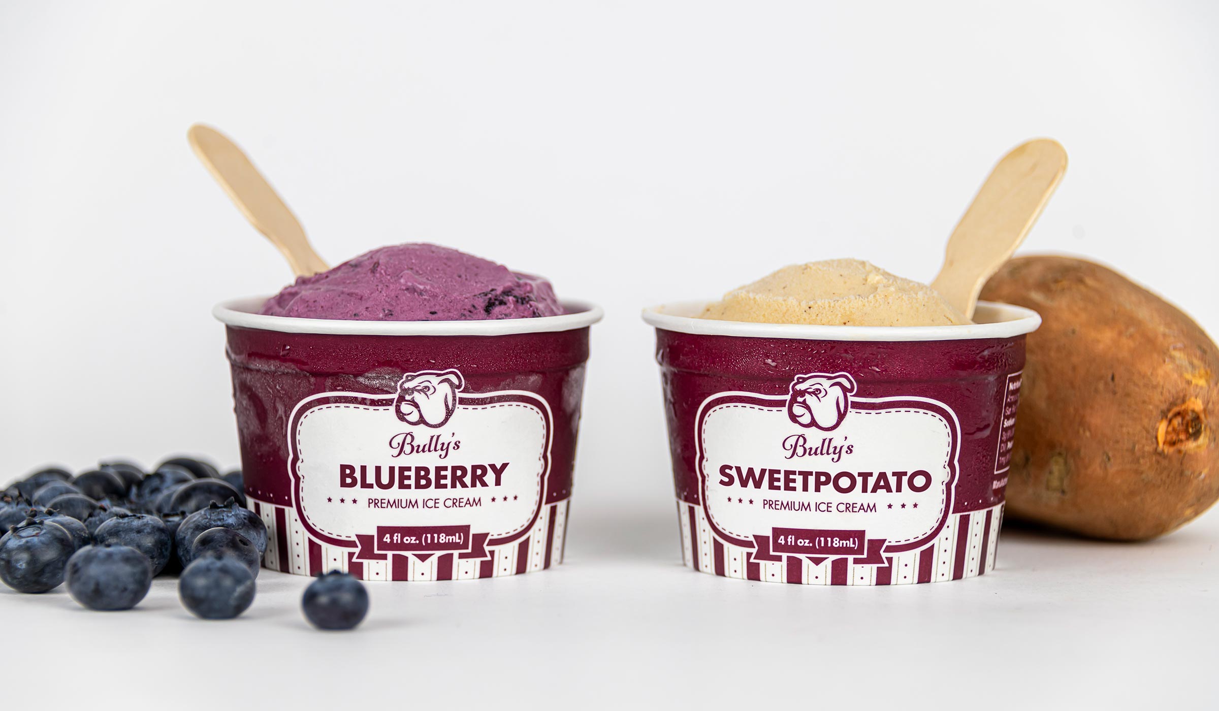 Two maroon and white ice cream containers with blueberries and sweet potatoes.