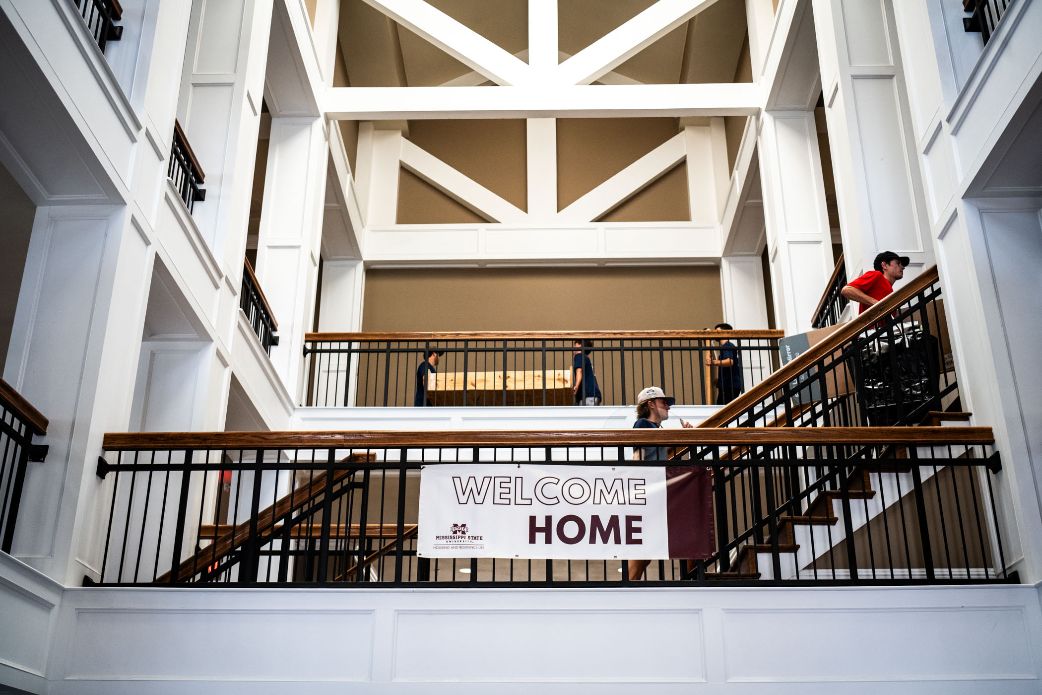 Students bring personal belongings into a residence hall and walk past a Welcome Home sign.