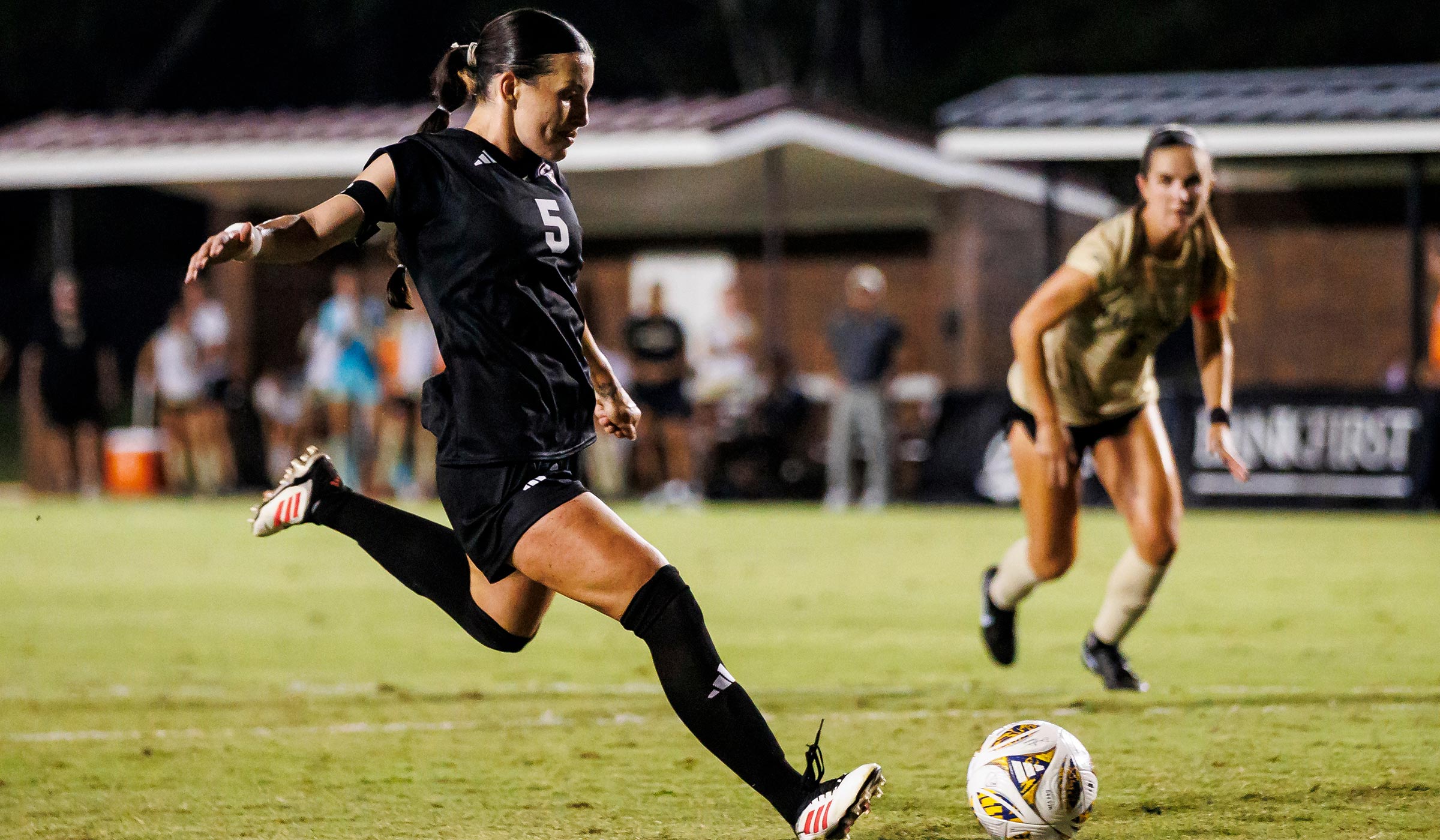 Female in black soccer uniform striking soccer ball