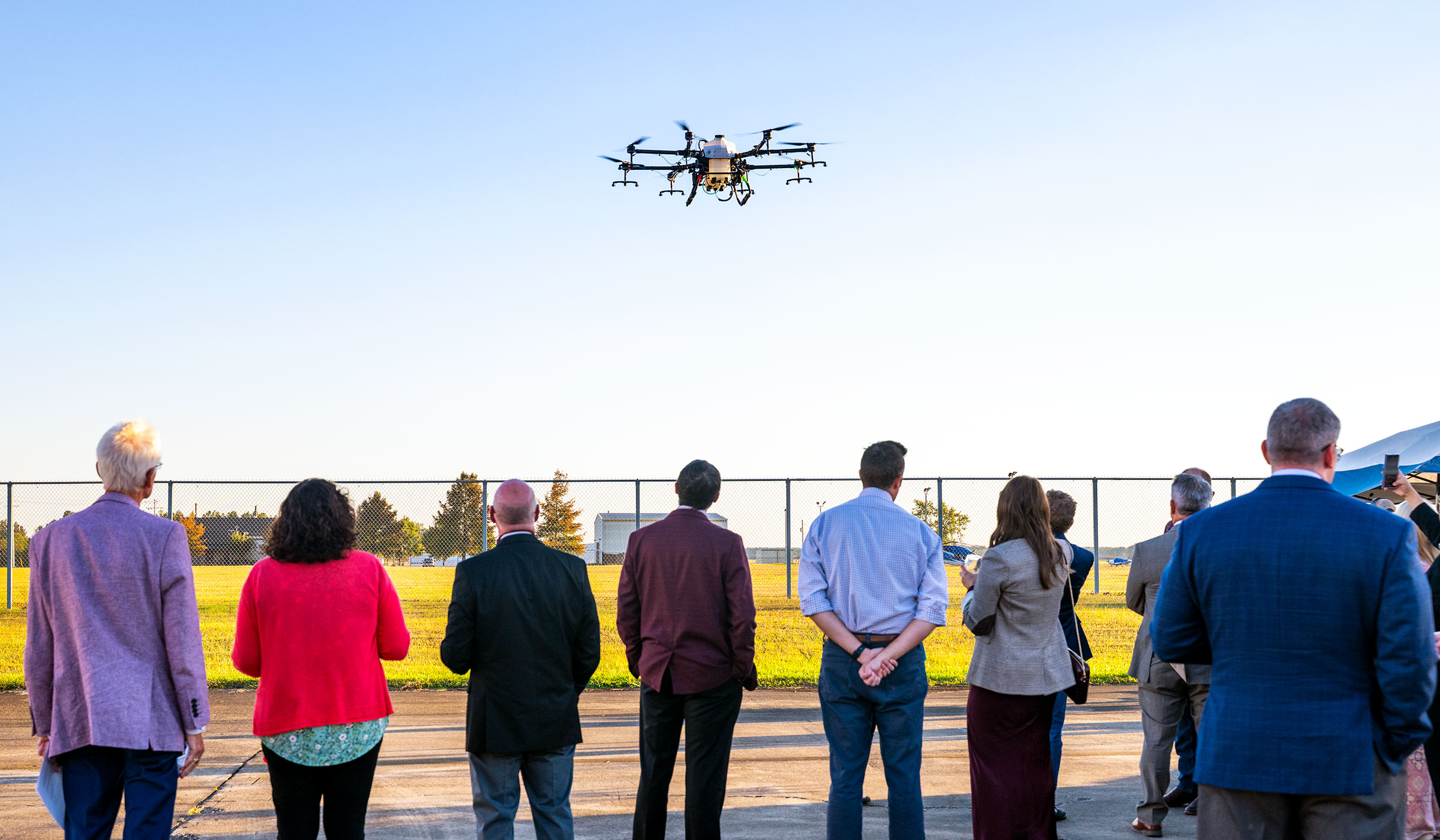 People watching UAV with container flying in air