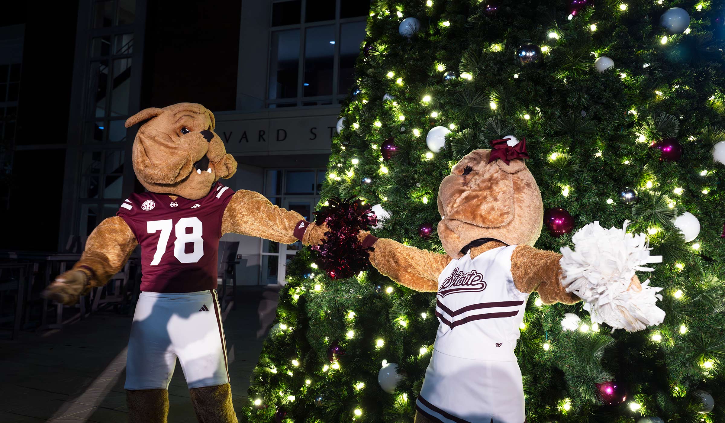 Costume bulldog mascots dancing in front of Christmas tree