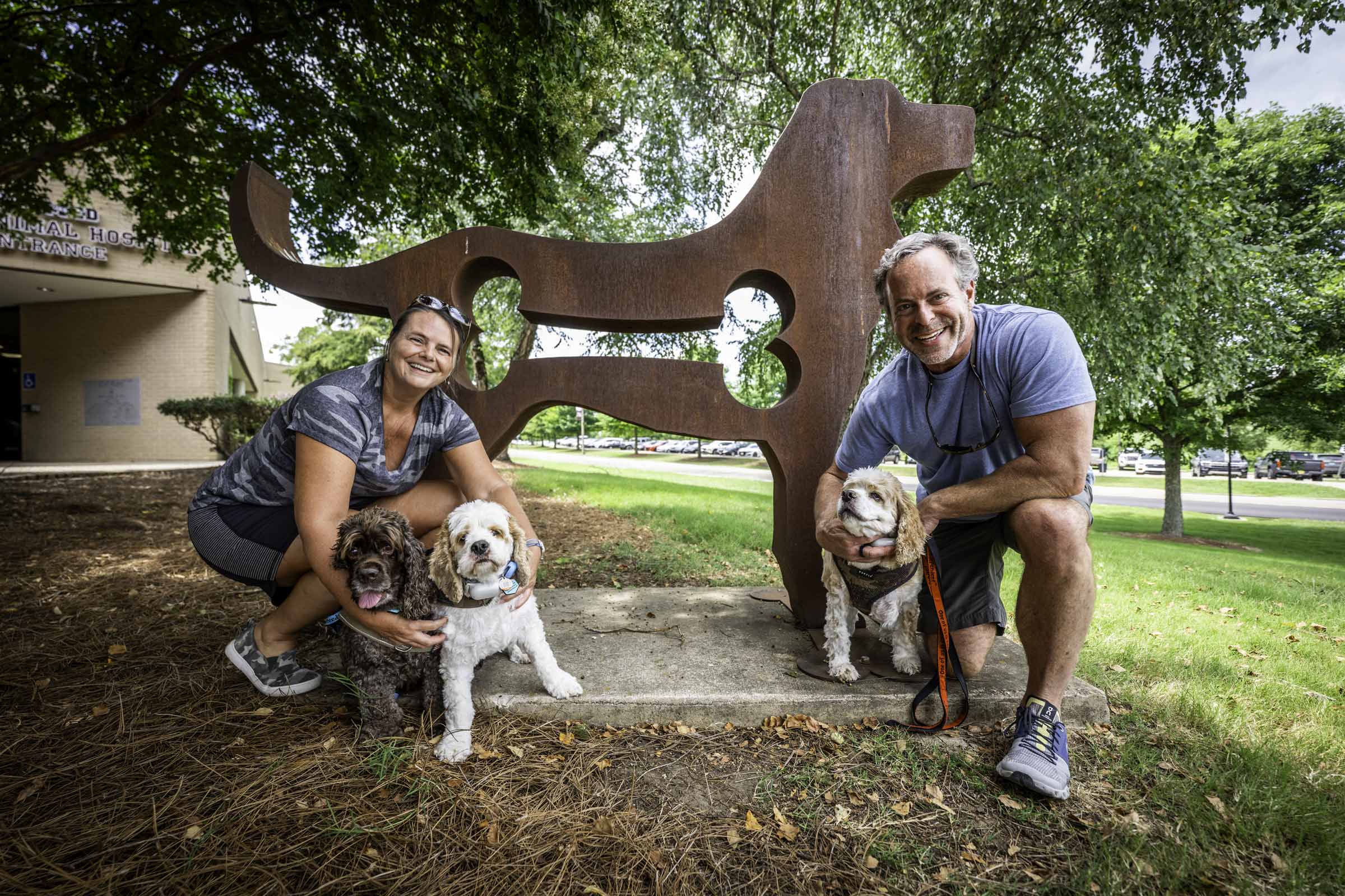 Jennifer Tillman and Calvin Kelly, Mississippi natives now living in Indianapolis, Indiana, pose with their cocker spaniels—Goose, Tucker and Chip—during a visit to Mississippi State University's College of Veterinary Medicine. Once a month, the couple travels to Starkville so the three dogs can receive specialized dermatology care from the college's veterinary team, a testament to the expertise that draws clients from across the country.