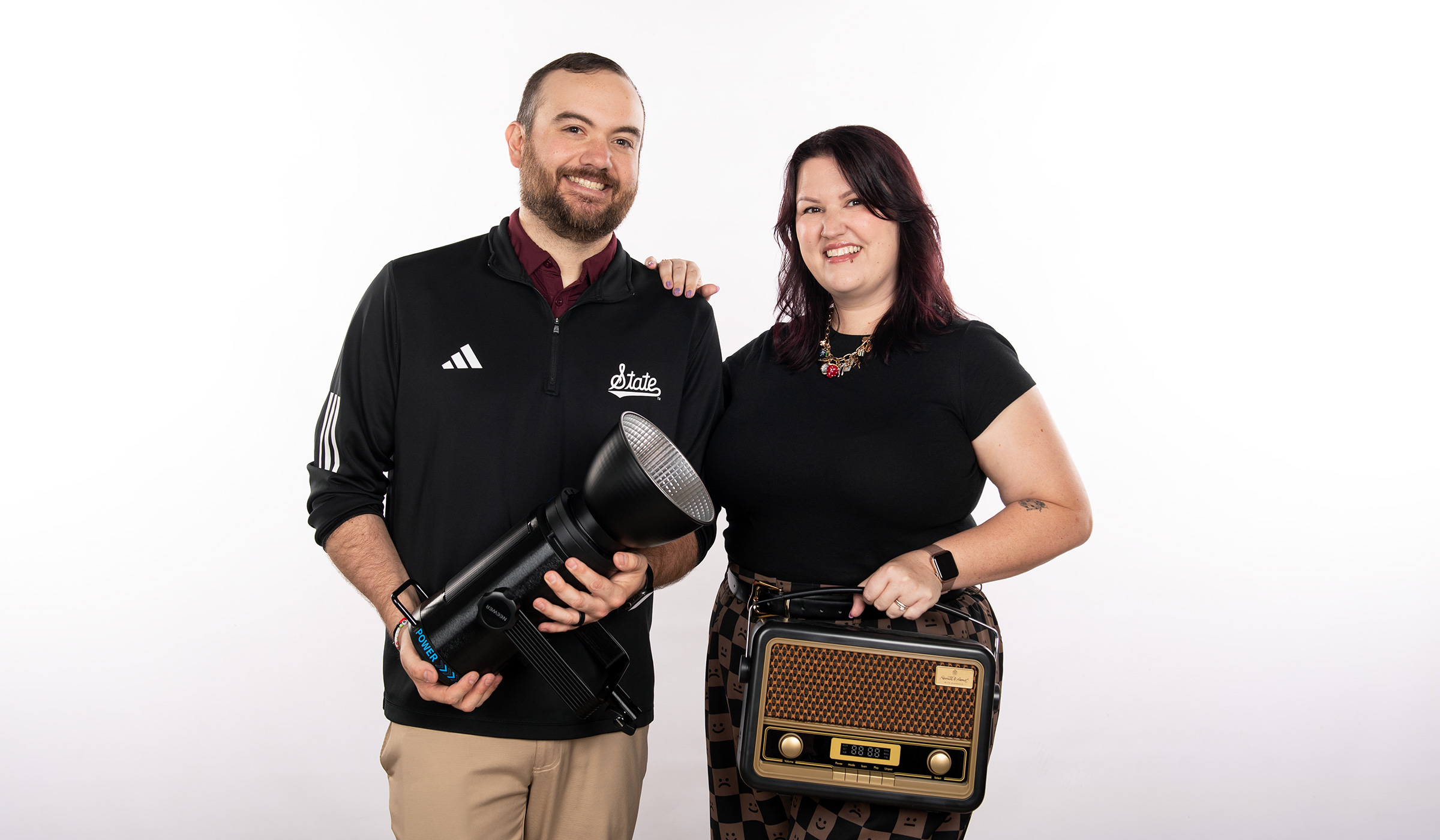 Greg Thorn, a Mississippi State lighting designer, and Becca Thorn, general manager of the university's radio station, posing with a studio light and a vintage radio