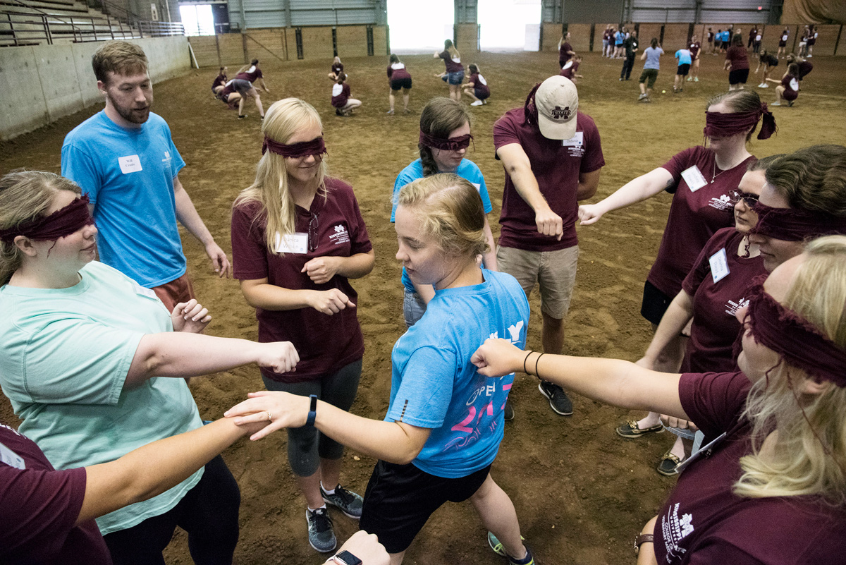 Blindfolded Freshmen Veterinary students stand in a circle around one student at the horse park as an ice-breaker exercise.  