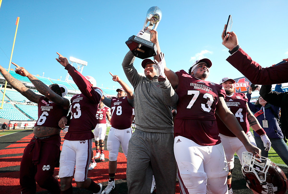 Football players hold the Taxslayer Bowl Trophy up in celebration of their 31-27 win.