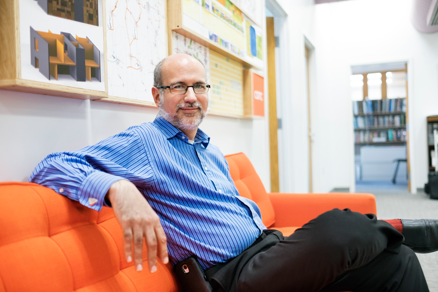 John Poros of MSU&amp;#039;s School of Architecture sitting on an orange sofa.