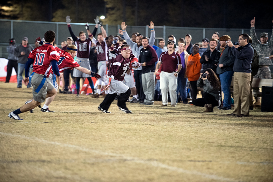 Special Olympics Mississippi athlete sprinting with a football and people cheering in the background