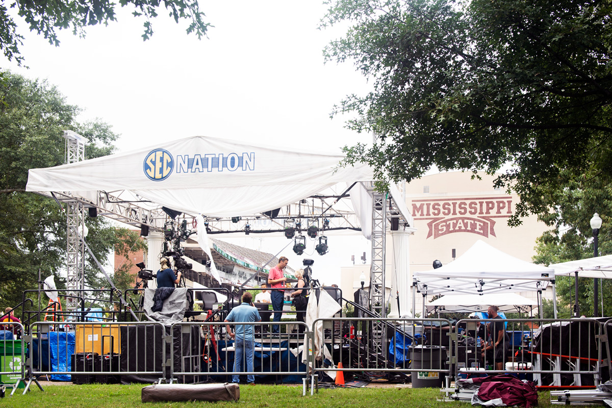 White tent with SEC Nation lettering in foreground with jumbo screen of Davis Wade in background