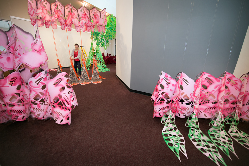 Visiting artist Liz Miller appears small in the Cullis Wade Depot, surrounded by her brightly colored felt and paper custom art.