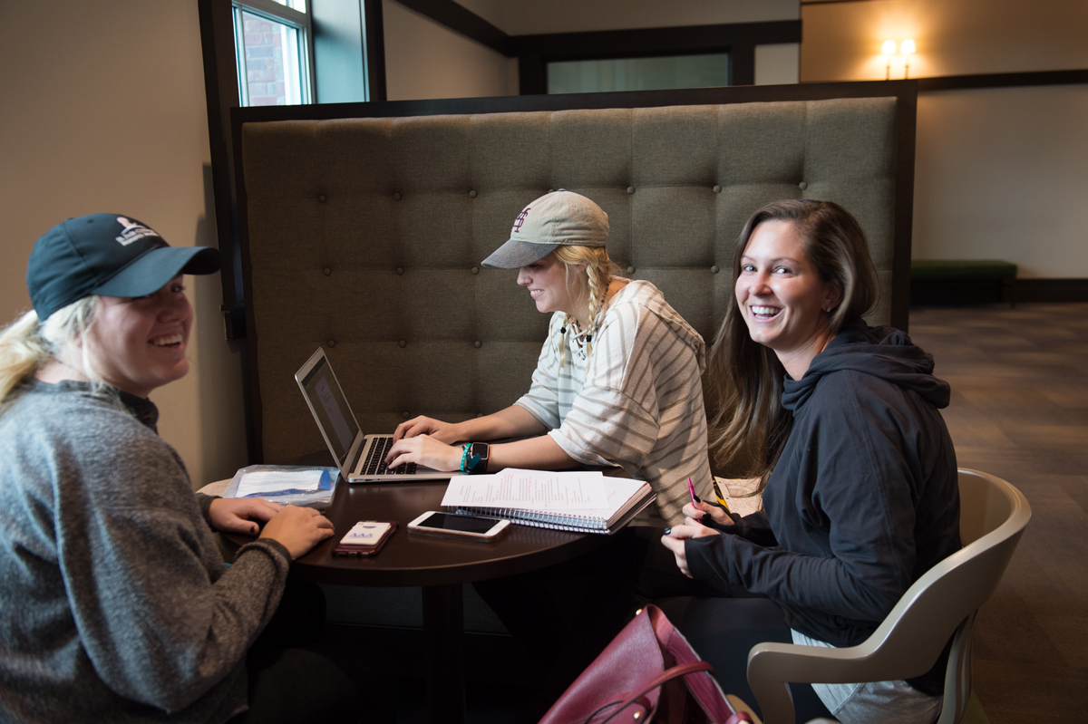 Three students cluster around a laptop in Old Main Academic Center, finishing up their group project, creating a fashion line.