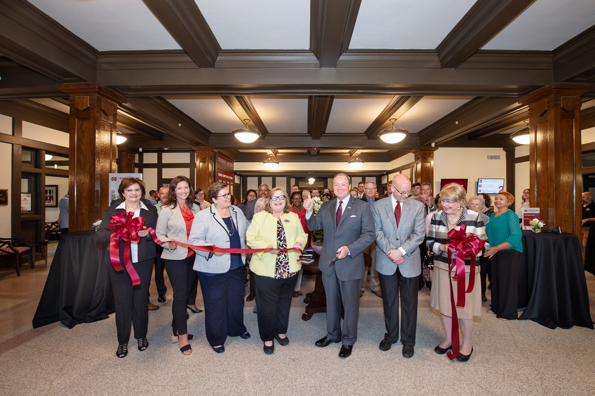 With the YMCA Building&amp;#039;s freshly renovated pillars and ceiling beams behind them, President Keenum cuts the re-opening ribbon.