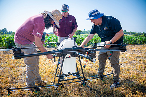 Personnel from Mississippi State and Leading Edge Aerial Technologies ready a spray drone for the field. 