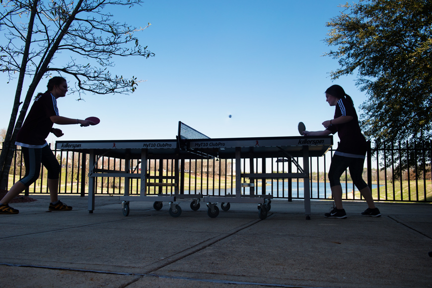 Amelia Andersson and Rebecca Siciliano pose by a ping pong table with Chadwick Lake in the background.