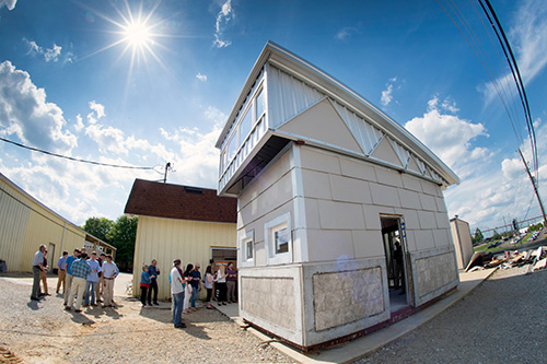 Students and others stand near the steel and concrete tiny house created as part of a two-semester construction project in MSU’s Building Construction Science program. Part of the College of Architecture, Art and Design, the program is one of only two studio-based construction programs in the U.S. (Photo by Megan Bean)