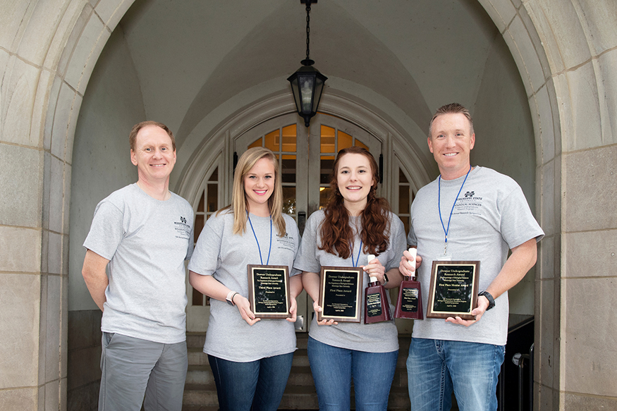 MSU Biological Sciences Department Head Angus Dawe, left, congratulates Biological Sciences Undergraduate Research Program symposium third place winner Rachel Fowler of Union City, Tennessee, first place winner Josi Lott of Memphis, Tennessee, and First Place Mentor Award Winner Justin Thornton. Not pictured is second place winner Christopher Lebeau of Harvest, Alabama. (Photo by Beth Wynn)