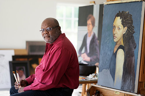Portrait of Alex Bostic with some of his paintings