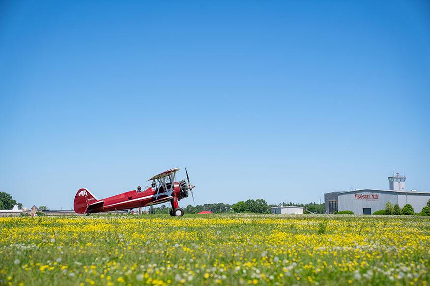 A maroon airplane is taxied at Bryan Field