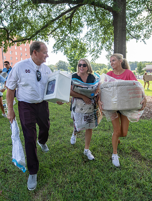 MSU President Mark E. Keenum and a parent help a new student carry personal belongings during the university's annual move-in day, MVNU2MSU.