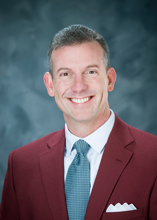 Studio portrait of Brent J. Fountain wearing blue tie and maroon coat