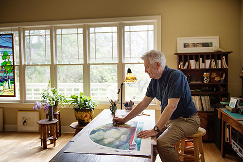 MSU art professor Brent Funderburk works on a watercolor painting in the studio at his Starkville home. (Photo by Megan Bean)