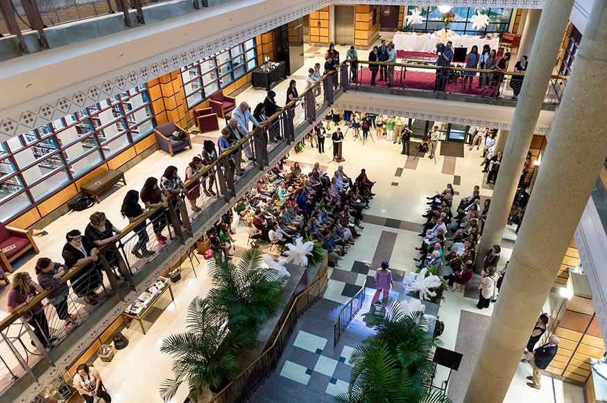 A crowd of people watches as a Gatsby Gala model descends the grand staircase at MSU’s Mitchell Memorial Library.