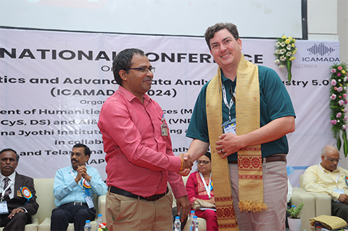 George Banzhaf is greeted by a conference host at the ICAMADA conference.