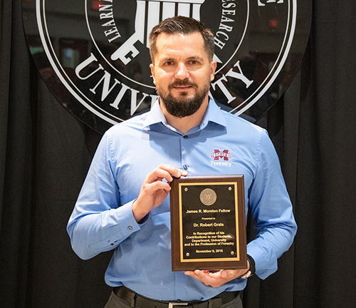 Robert Grala is pictured with a plaque commemorating his designation as a James R. Moreton Fellow during a recent awards luncheon. (Photo by David Ammon)