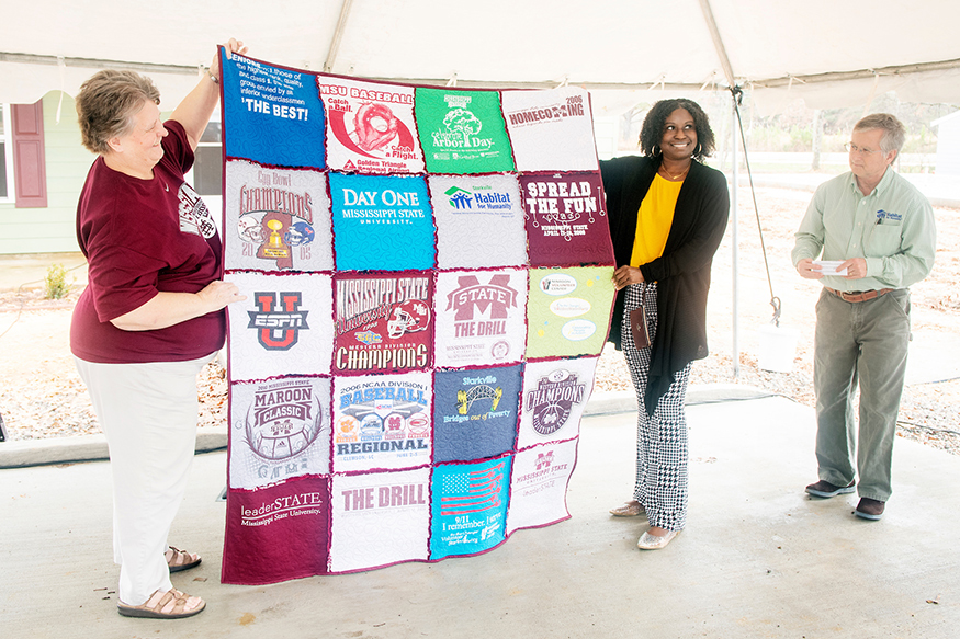 Starkville resident Dot Livingston and new homeowner Keyana Triplett hold a T-shirt quilt during the 11th Maroon Edition home dedication ceremony.