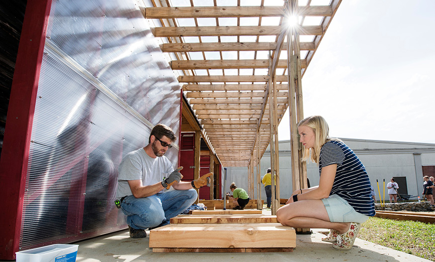 Cory Gallo, MSU associate professor of landscape architecture, guides senior landscape architecture major Caitlin Buckner of Starkville as she works to install cedar steps at the MSU Community Garden. (Photo by Megan Bean)