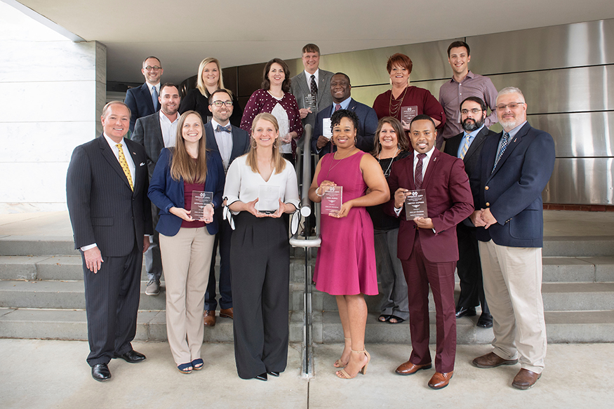 MSU President Mark E. Keenum and MSU Leadership Development Program Coordinator Brad Skelton stand with MSU's 15 LDP graduates on the steps outside the Hunter Henry Center.