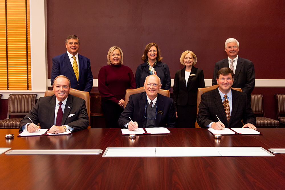 People sign an agreement in Dr. Mark Keenum's office