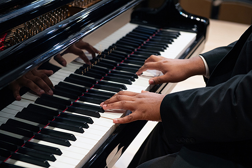 A person's hands are pictured as they play a piano.