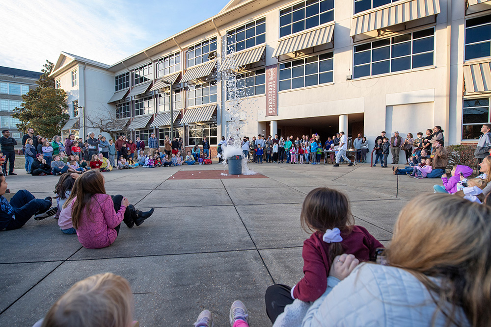 A large crowd gathers around a chemistry demonstration outside Hilbun Hall