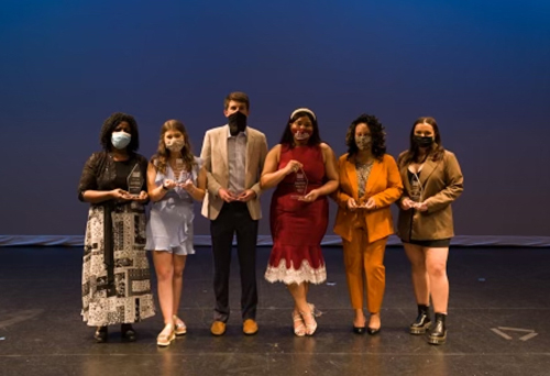 Students are pictured holding awards on stage