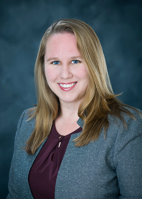 Studio portrait of Courtney Thompson wearing a maroon blouse and gray blazer