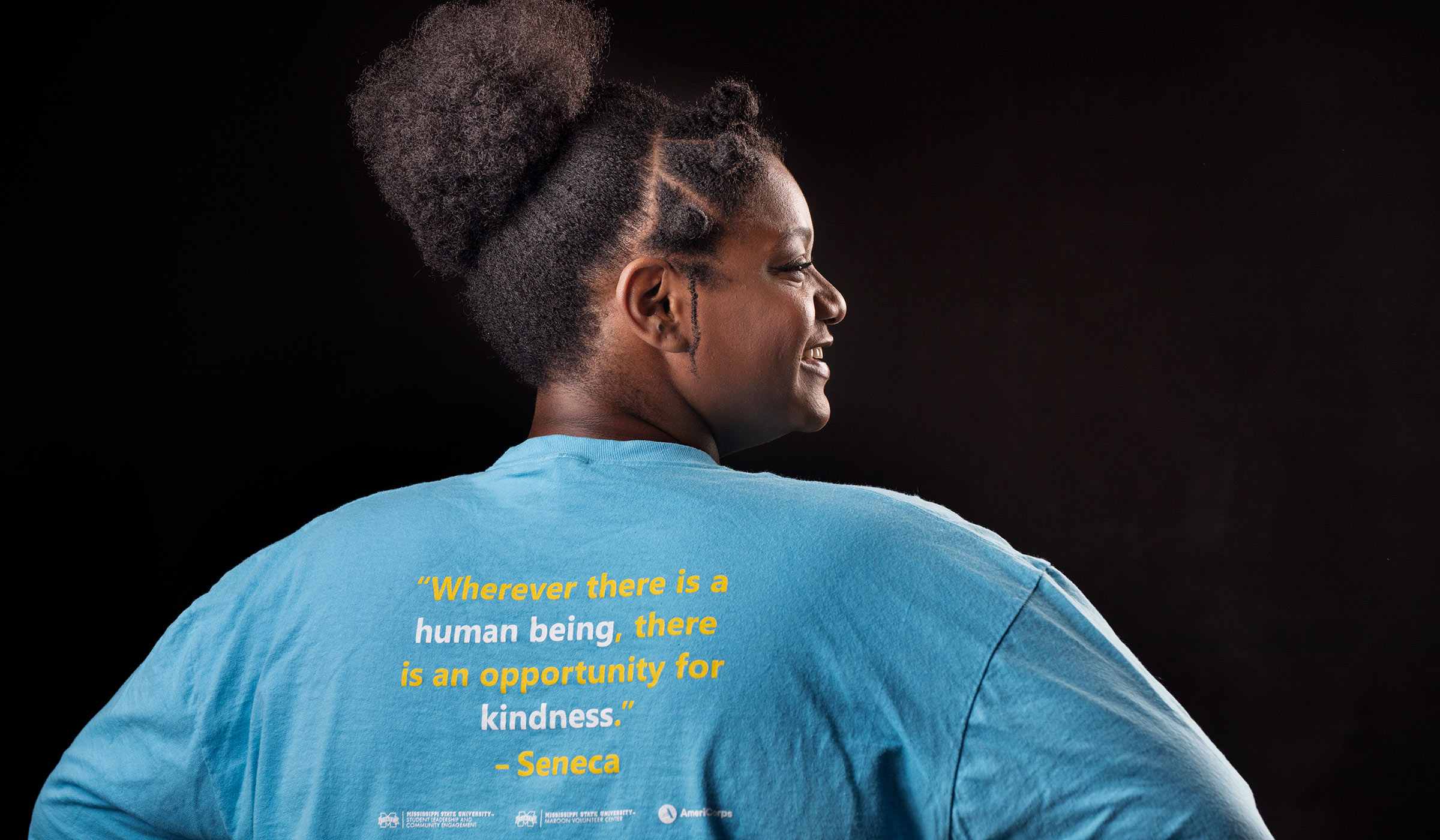 Alexis Wallace, pictured from behind, wearing a T-shirt with a quote that says "Wherever there is a human being, there is an opportunity for kindness." -- Seneca