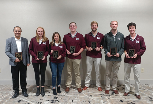 One professor and six students hold plaques