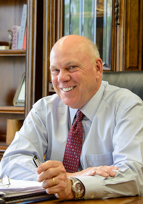 George M. Hopper smiles while seated at his office desk.