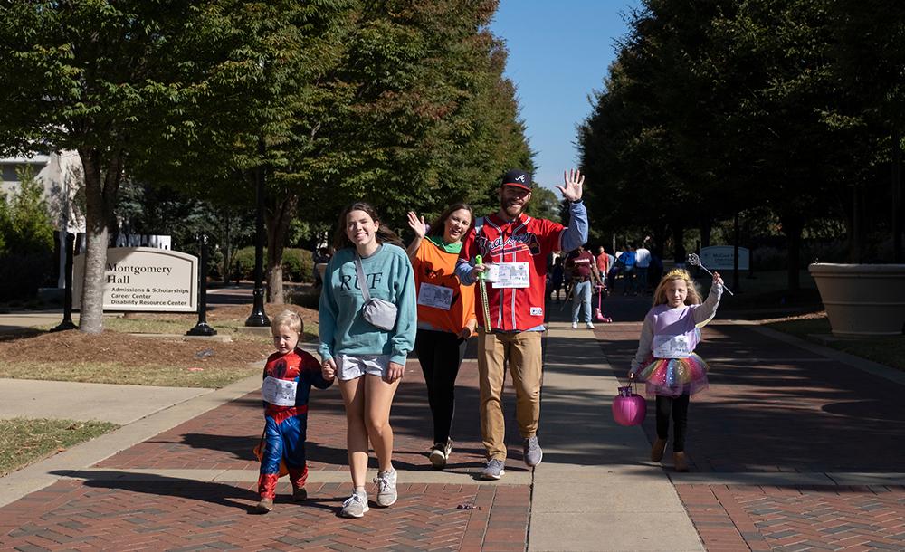 Adults and children walk along the sidewalk at Mississippi State.